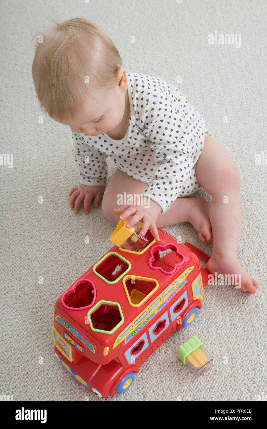 Baby Junge sitzt auf dem Teppich Spielen mit Lernen Spielzeug Stockfoto