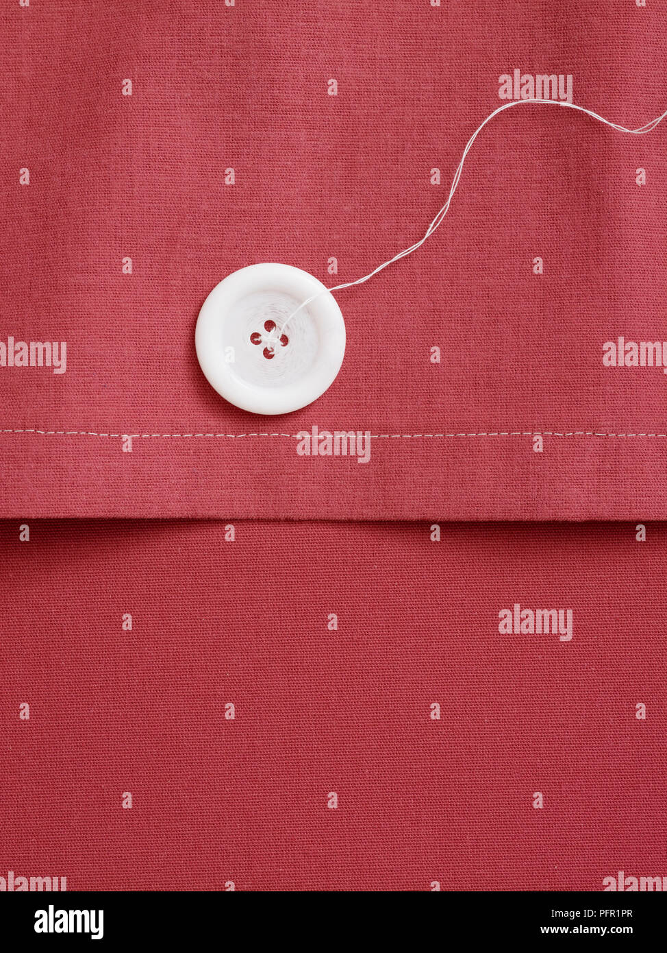 Weißen Knopf und Baumwollfaden auf Rosa Bett Polsterbezüge, close-up Stockfoto