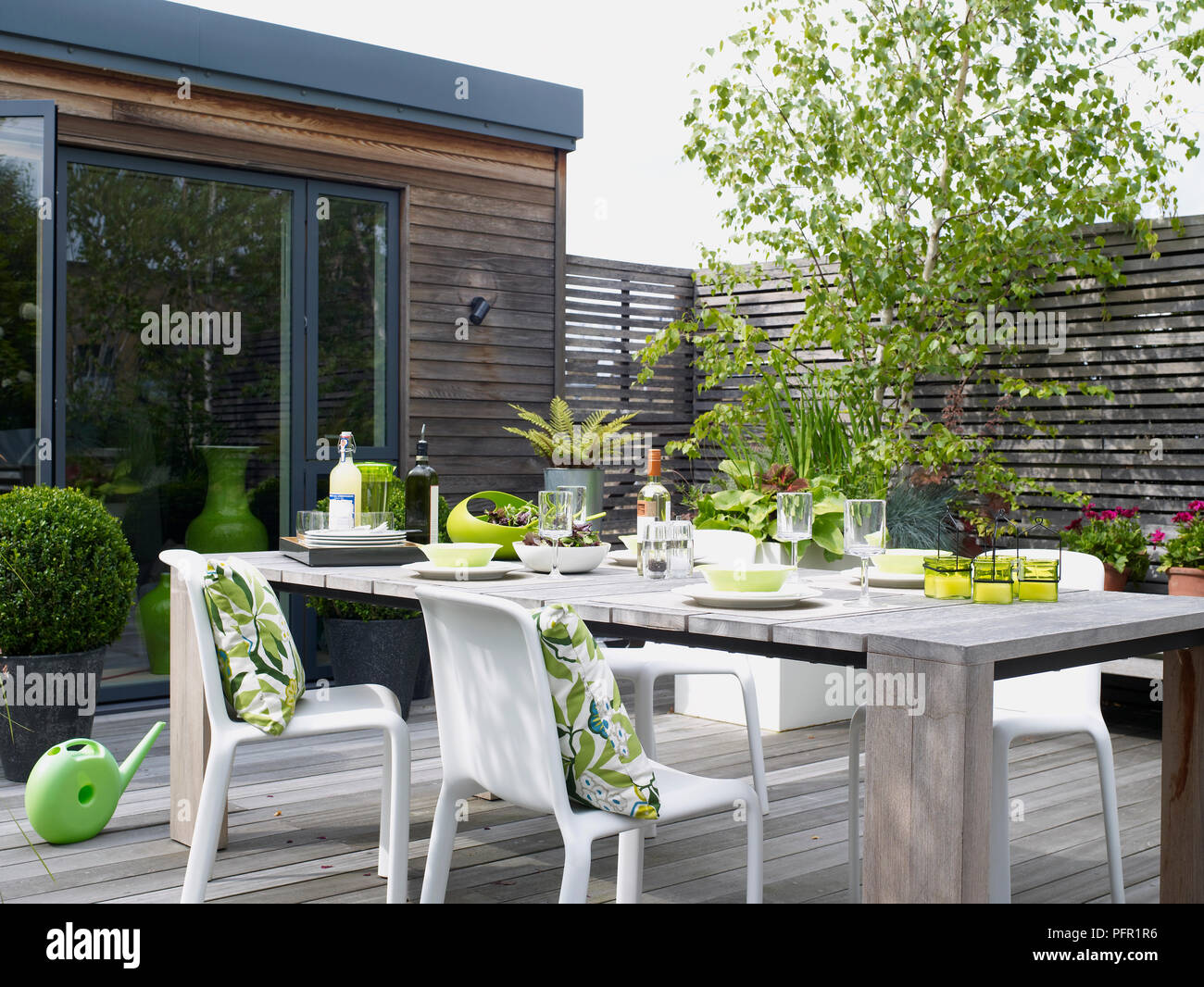 Holz Tabelle Fur Ess Und Floralen Muster Kissen Auf Weissen Plastikstuhlen Auf Uberdachte Terrasse Gesetzt Seitenansicht Stockfotografie Alamy