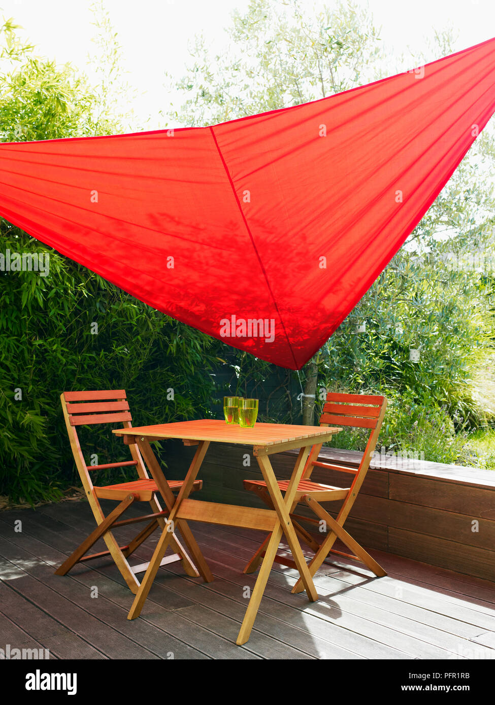 Rote Garten sail Schattenspender für Holz- Tisch und Stühle auf, überdachte Terrasse im Garten Stockfoto