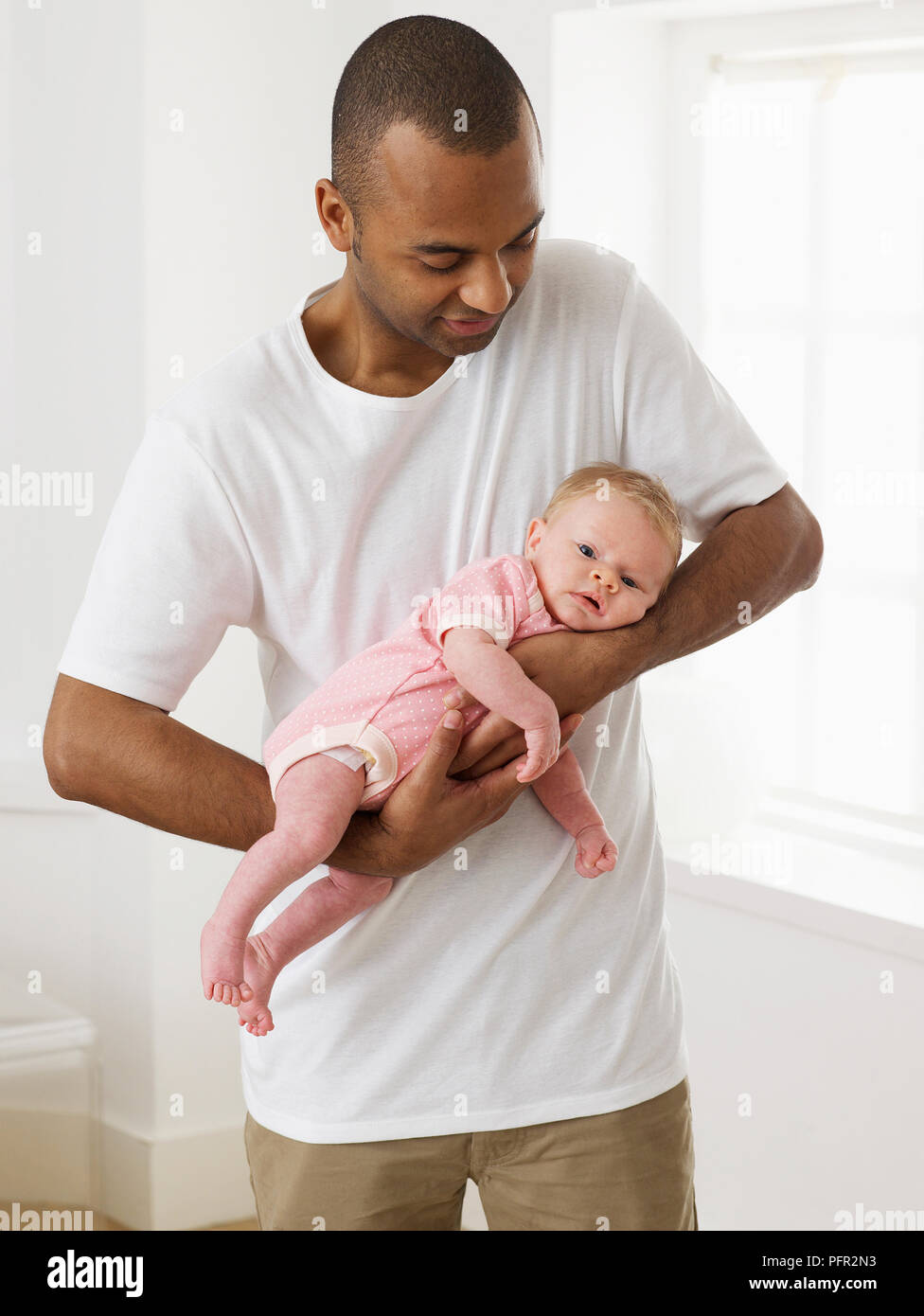 Mann hält Baby Mädchen in der Tiger halten, 4 Wochen Stockfoto