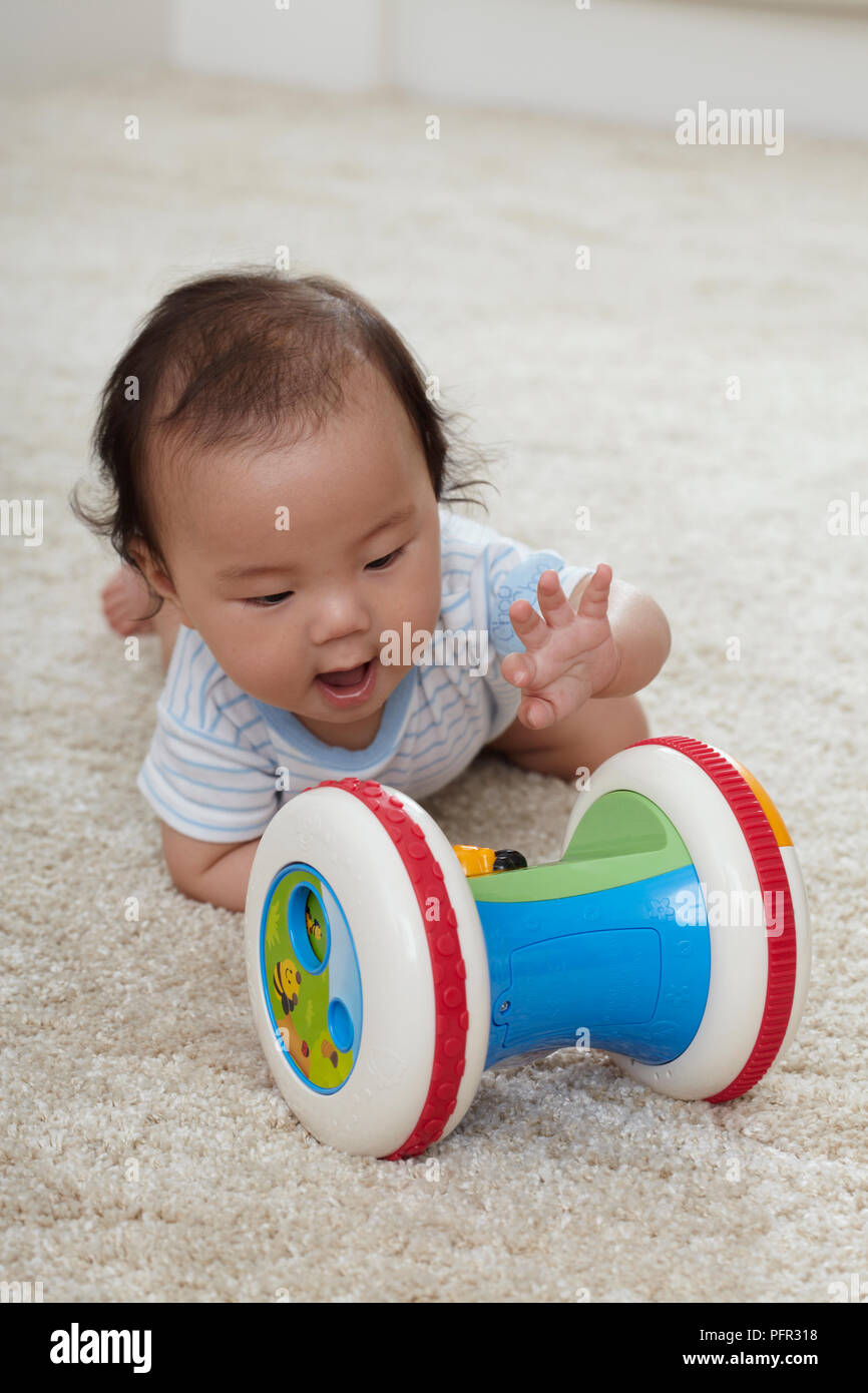 Baby Boy (6 Monate) erreichen für Kunststoff Spielzeug Rassel Stockfoto