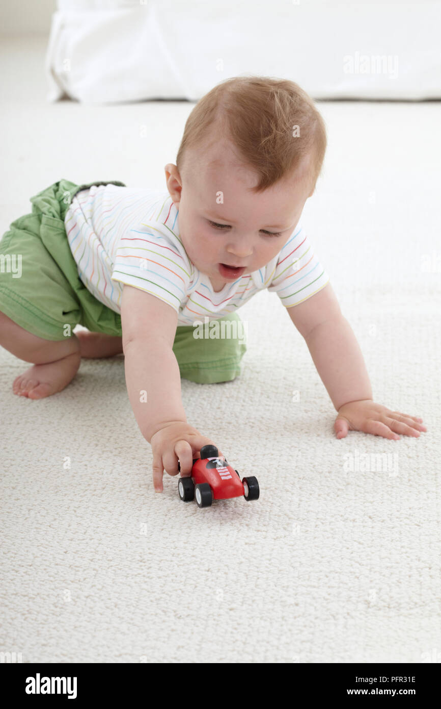 Baby Boy (9 Monate) spielen mit Spielzeug Auto Stockfoto