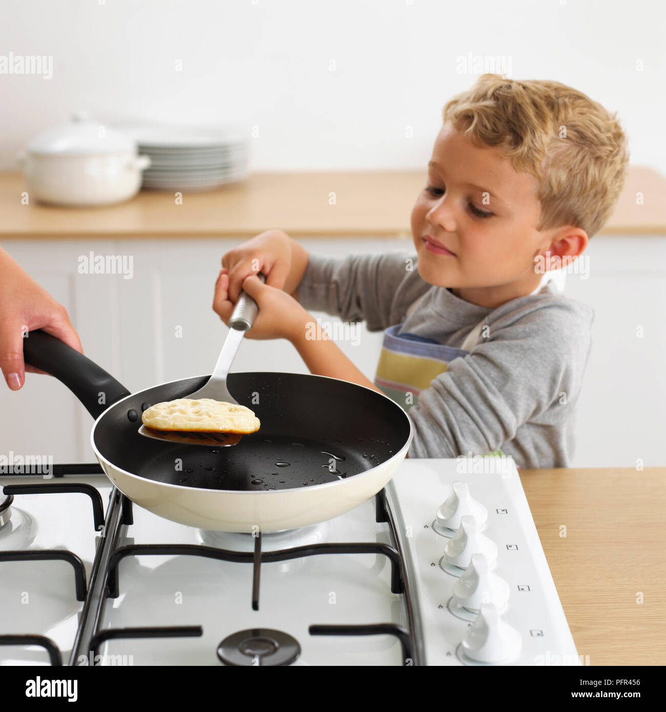 Junge spiegeln ein Pfannkuchen in einer Pfanne mit einem Spachtel, 4 Jahre Stockfoto
