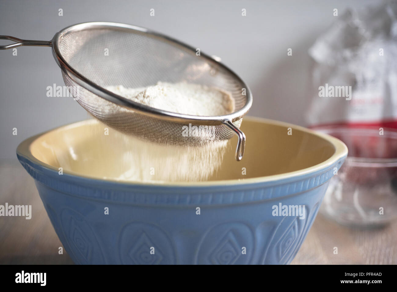 Mehl in eine Rührschüssel sieben Stockfoto