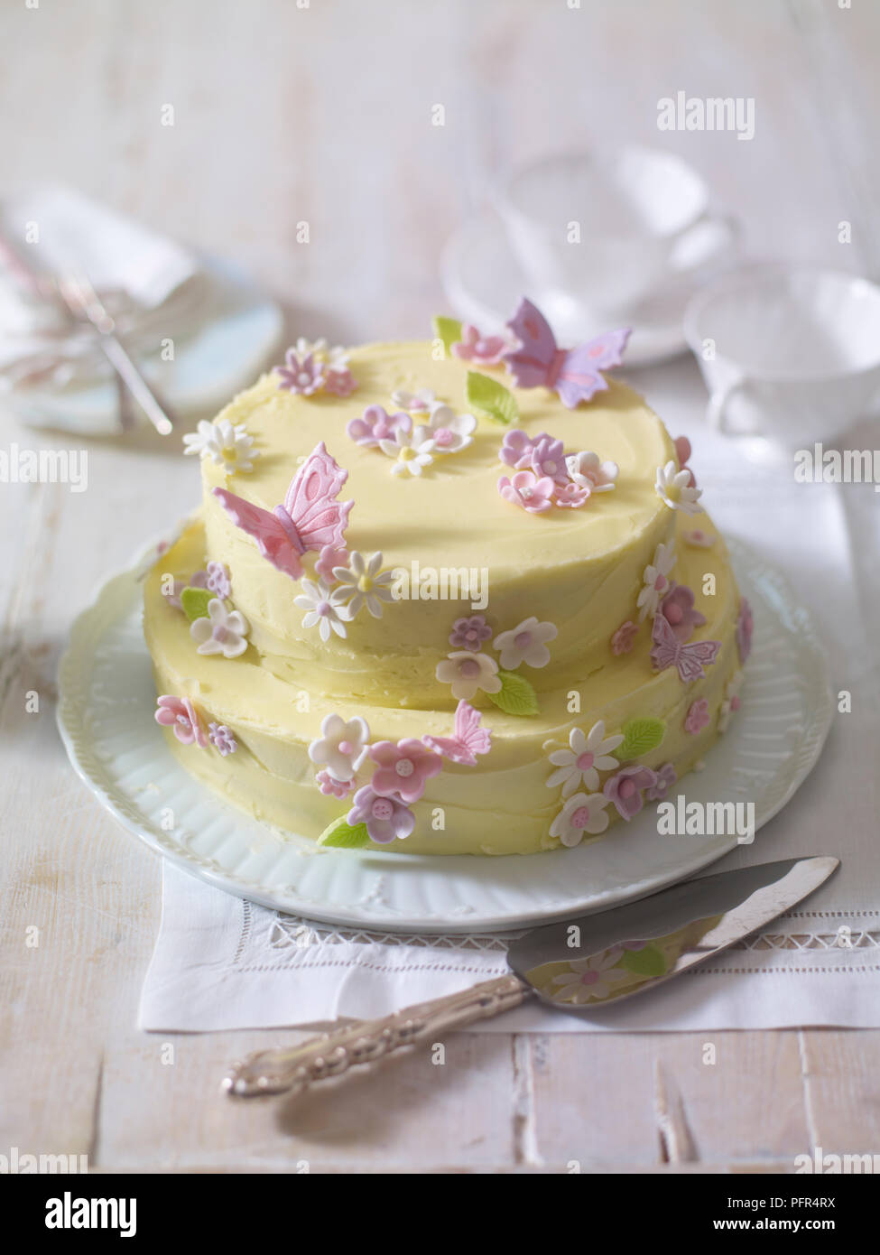 Zweistufige iced Kuchen dekoriert mit Blumen und Schmetterlingen aus Puderzucker Stockfoto