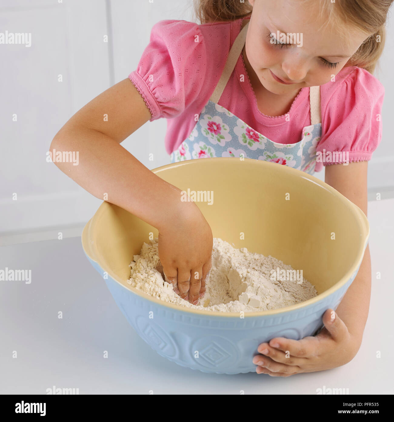 Mädchen ein Gut in eine Schüssel Mehl mit ihrer Hand, die Herstellung von Brot, 5 Jahre Stockfoto