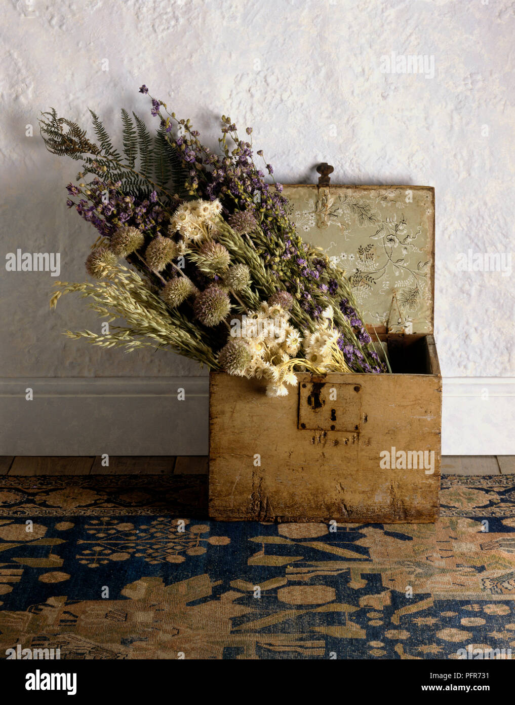 Getrocknete Hafer, Strohblumen, weiblichen Farn, Globus Distel, und larkspur Blumen im Bund im 18. Jahrhundert Holzkiste auf alten persischen Teppich Stockfoto