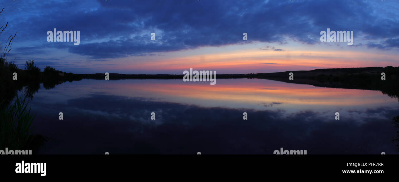 Ein Panorama von einem See am RSPB St Aidan's Natur Park kurz nach Sonnenuntergang mit nahezu perfekten Reflexionen. Stockfoto