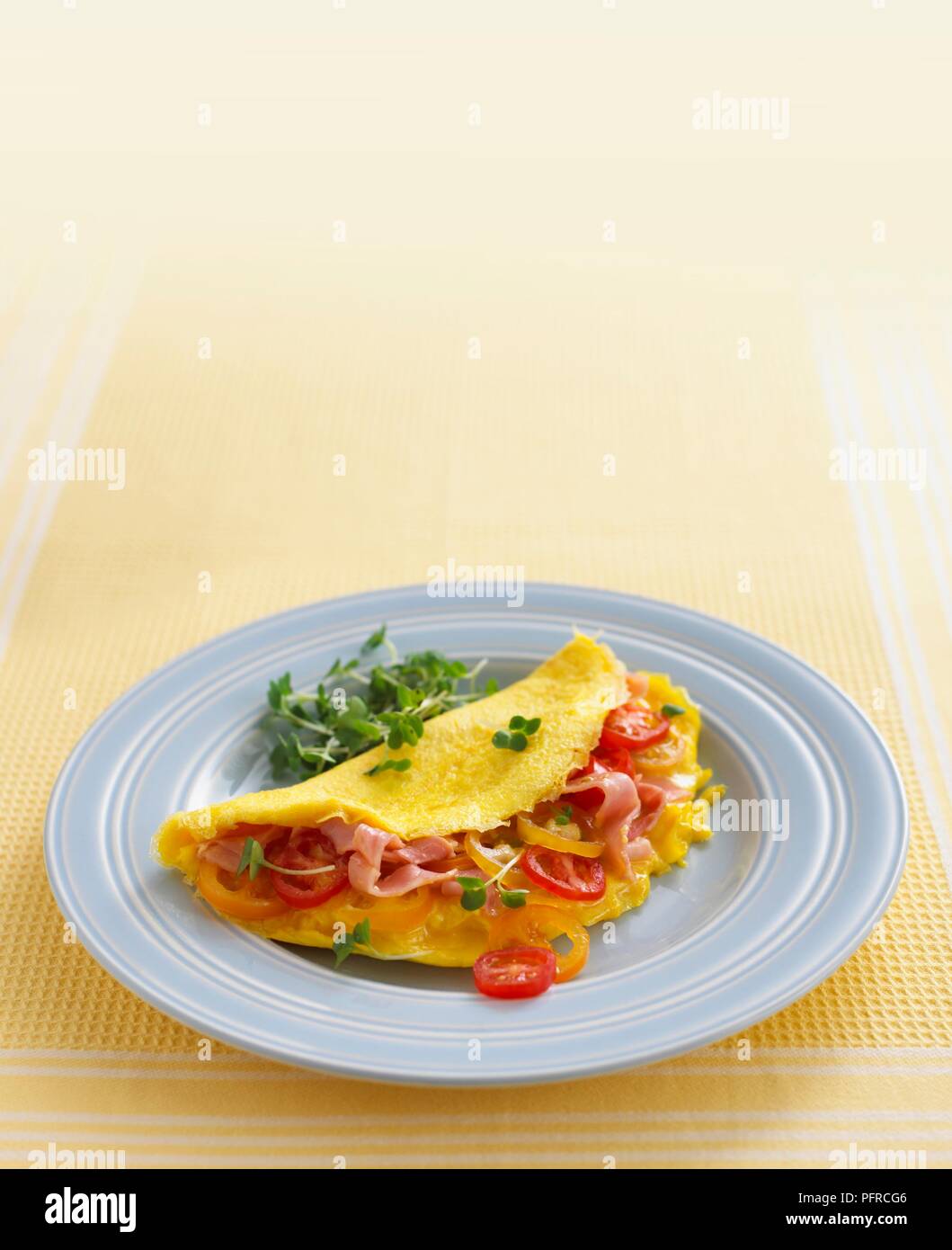 Schinken und Tomaten Omelette auf blaue Platte mit Kresse Stockfoto
