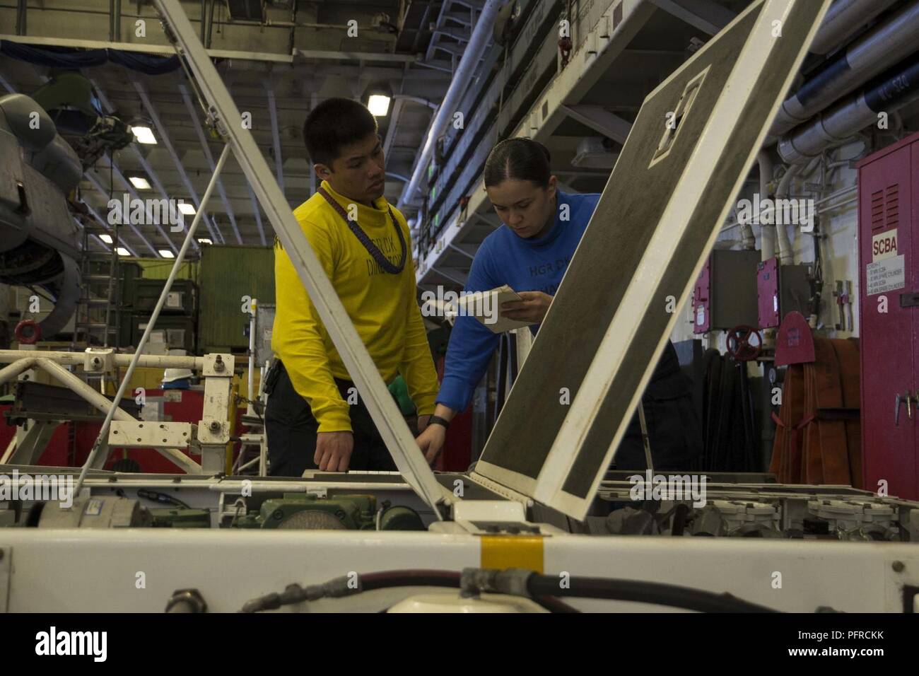 5. Flotte BEREICH VON OPERATIONEN (28. Mai 2018) der Luftfahrt Bootsmann Mate (Handling) 3. Klasse Jules Alminar (links), aus San Diego, Züge der Luftfahrt Bootsmann Mate (Handling) Airman Victoria Pina, von Aurora, Colorado, wie pre-Funktionsprüfungen an einem AS-32 EIN spotting Dolly im Hangar Bucht von der WASP-Klasse amphibisches Schiff USS Iwo Jima, 28. Mai 2018 durchführen zu können. Iwo Jima in Mayport, Fla. homeported, ist auf die Bereitstellung zu den USA 5 Flotte Bereich für Maßnahmen zur Erhöhung der Sicherheit des Seeverkehrs Operationen Verbündeten und Partnern zu beruhigen, und der Freiheit der Schiffahrt und des Free Flo bewahren Stockfoto