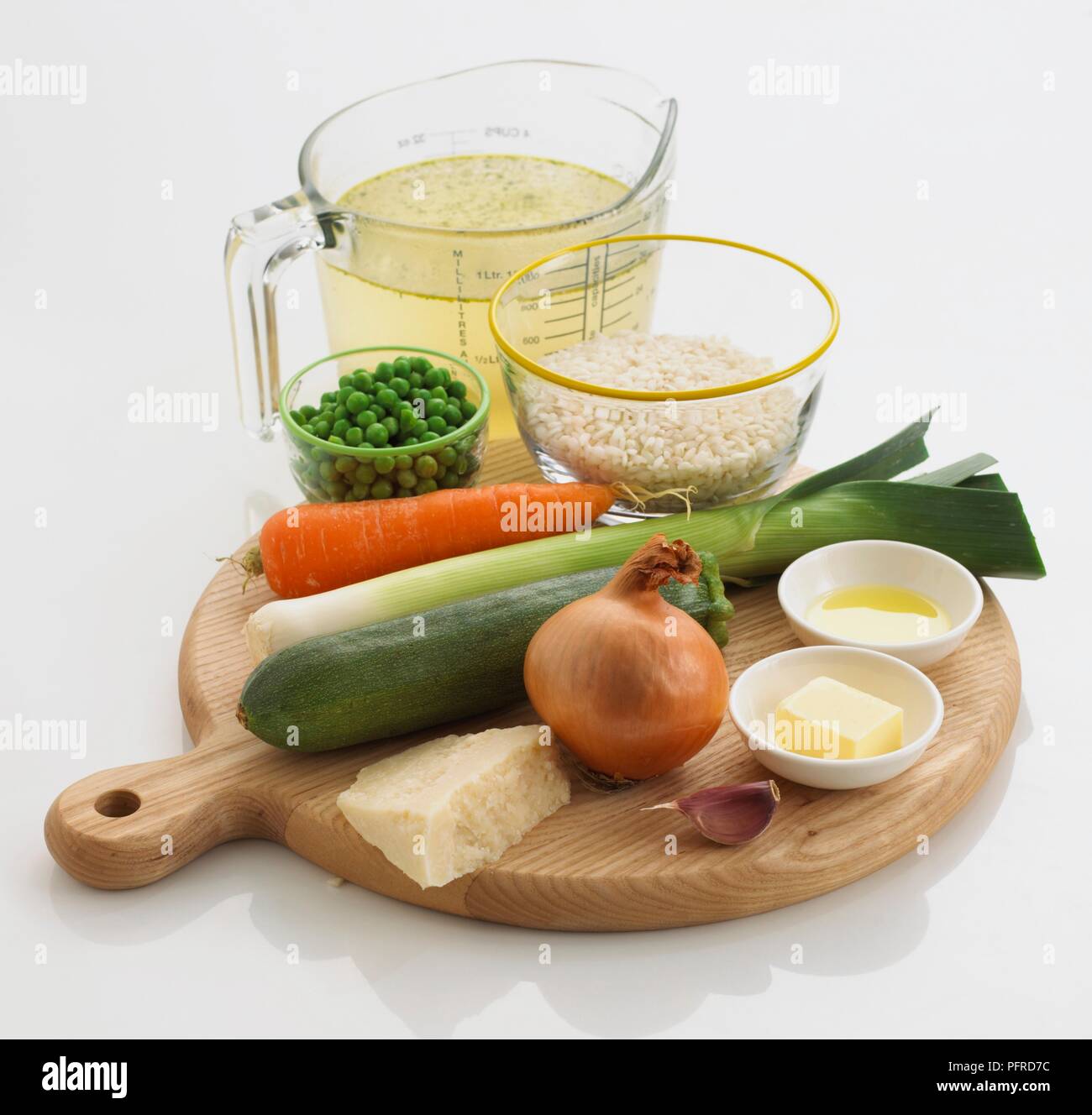 Zutaten für ein Risotto, wie Risotto Reis, Lagerbestand, Erbsen, Karotten, Lauch, Zucchini, Zwiebel, Parmesan, Knoblauch, Butter, Olivenöl Stockfoto