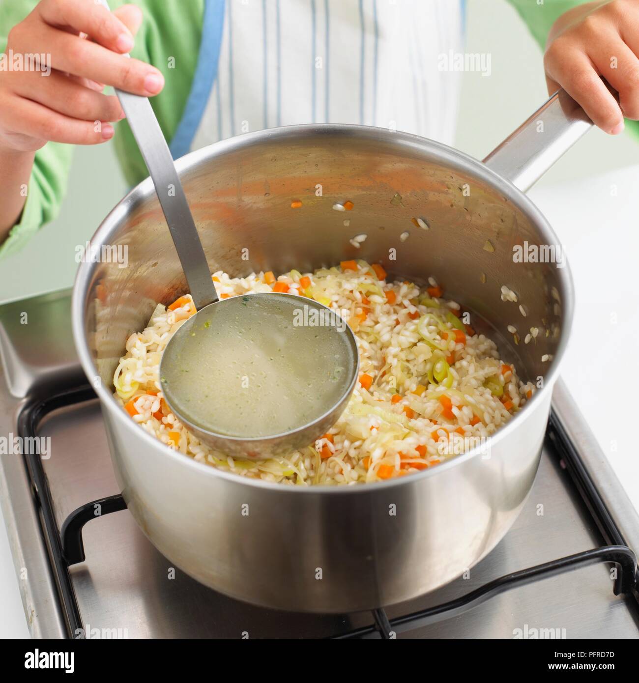 Mädchen Lager hinzufügen zu einem Gemüse risotto in Pan, close-up Stockfoto