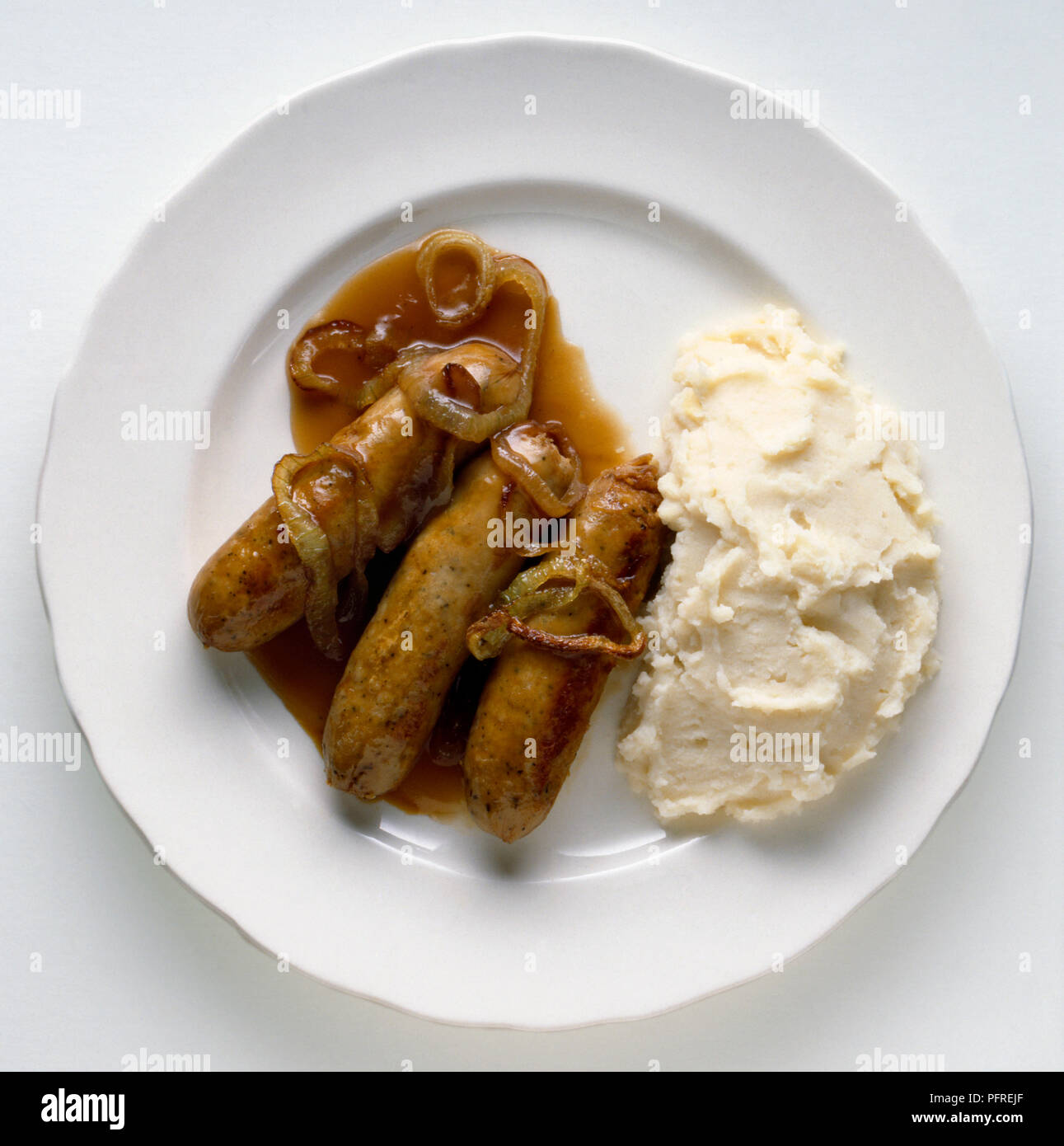 Würstchen mit Kartoffelbrei mit Zwiebel Soße auf weiße Platte Stockfoto