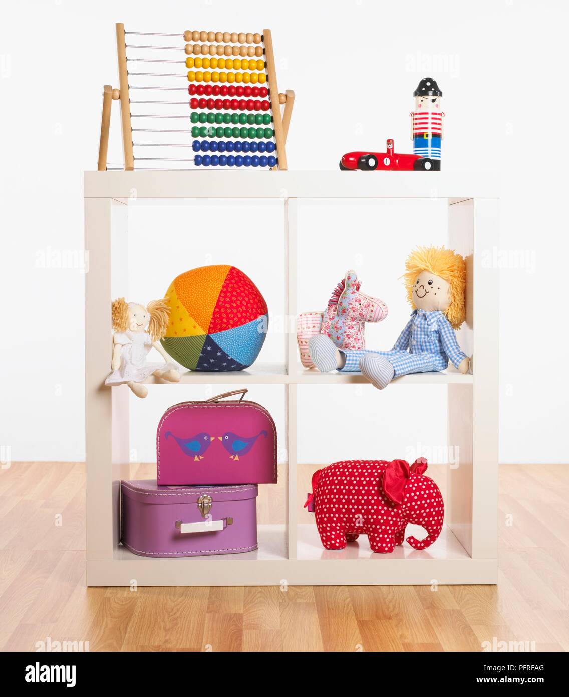 Verschiedene Spielzeuge im Bücherschrank, inklusive Koffer, gefüllt Spielzeug, Ball, abacus Stockfoto