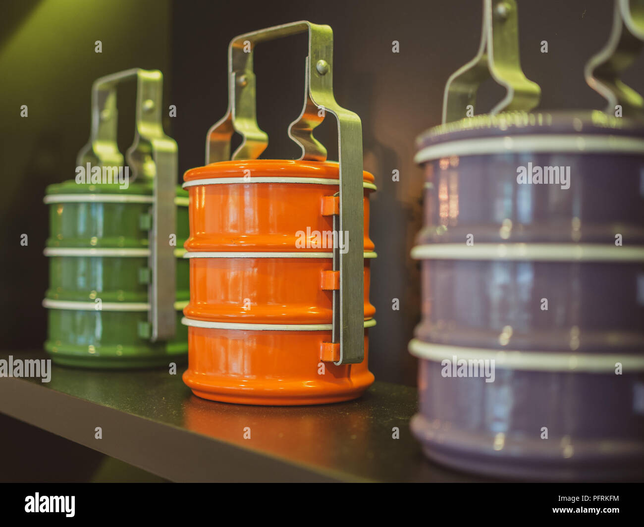 Orange, Violett und Grün tiffin Träger. Bunte vintage food Carrier auf Holzregal. Stockfoto