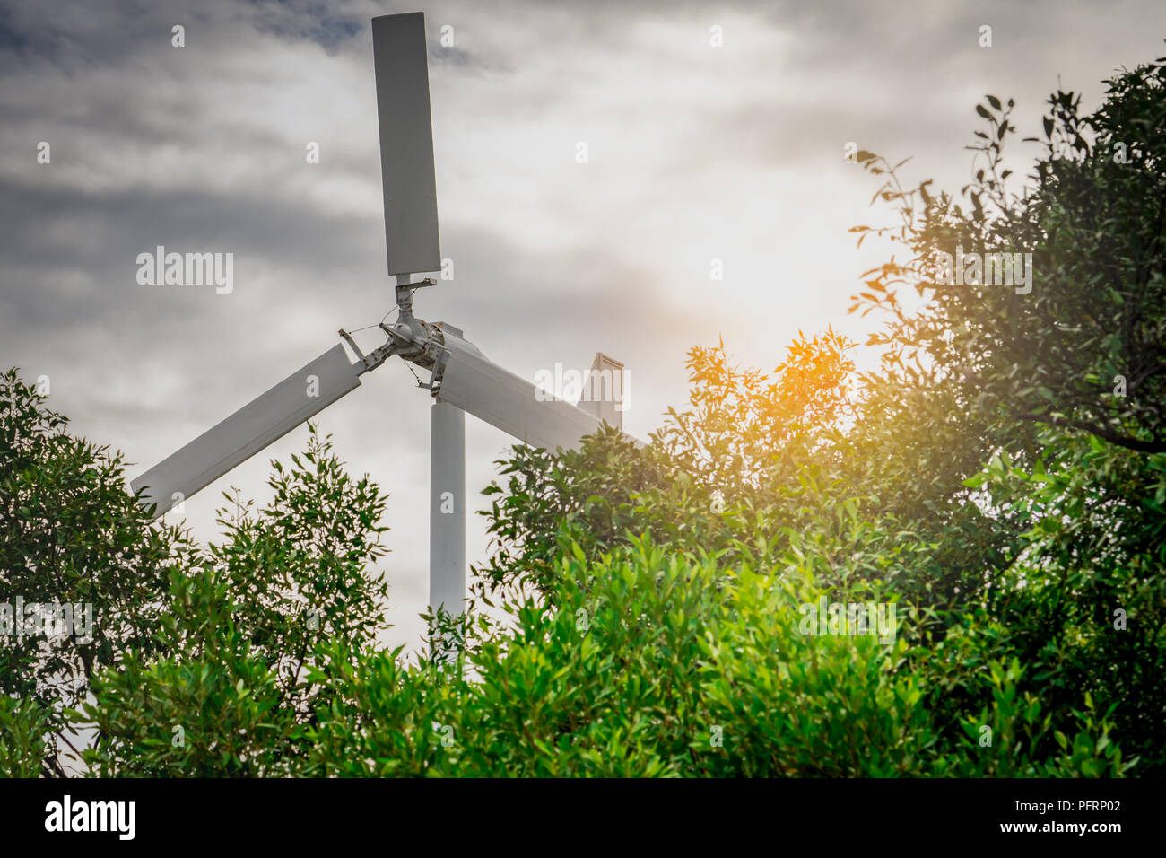 Horizontale Achse Windkraftanlage mit blauem Himmel und weißen Wolken in der Nähe von grünen Bäumen. Windenergie in Eco-Windparks. Grüne Energie Konzept. Erneuerung der Energie. Ändern Stockfoto