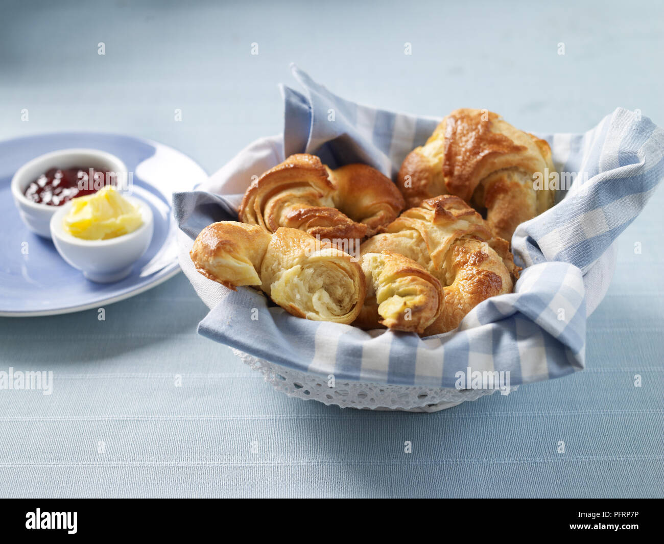 Körbchen mit Croissants, Butter und Marmelade Stockfoto