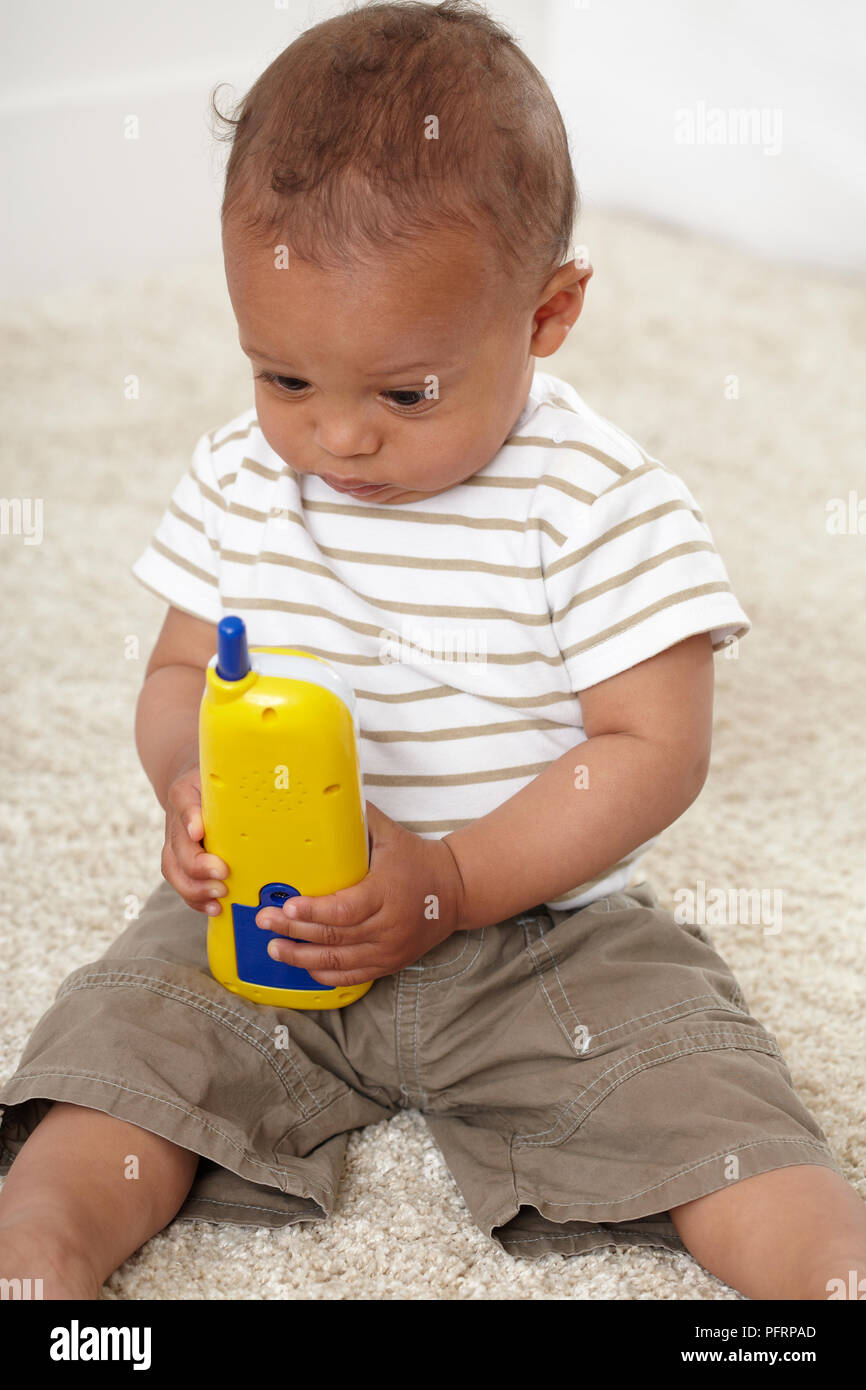 Baby Boy (8 Monate) Holding Kunststoff Spielzeug Telefon Stockfoto