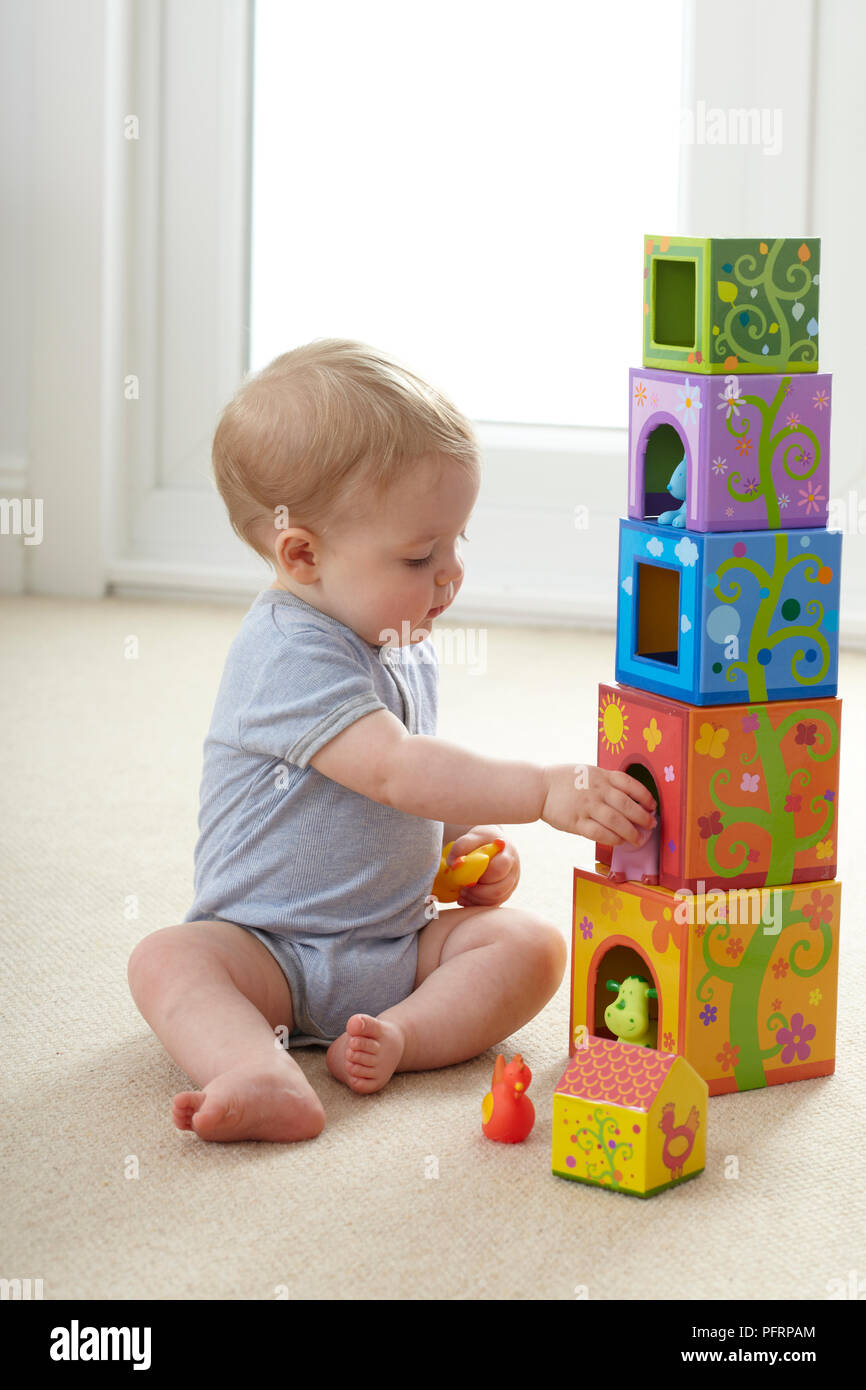 Baby Boy (12 Monate) sitzt auf dem Boden und mit Spielzeug spielen Stapel Stockfoto