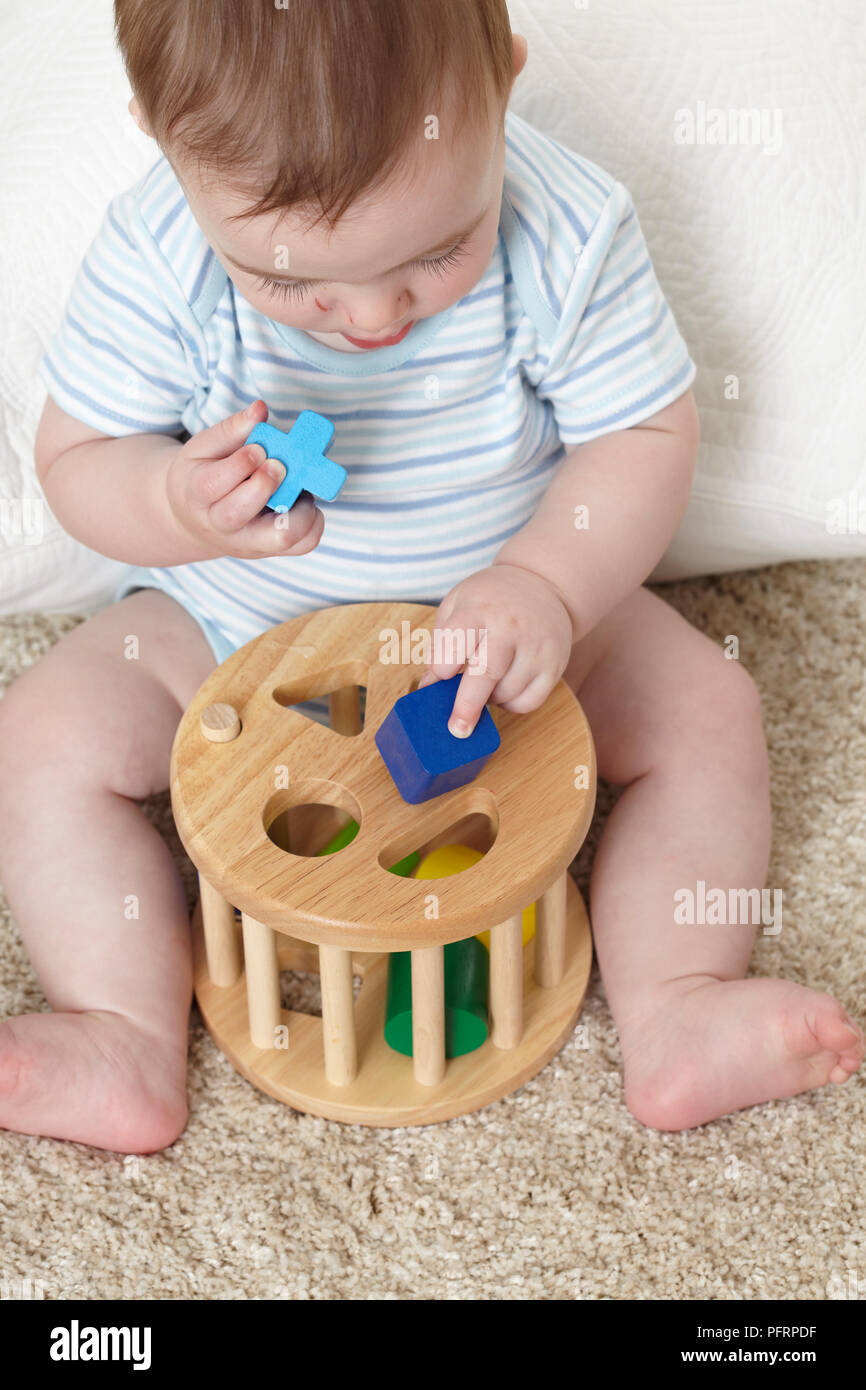 Baby Boy (32 Wochen) spielen mit Holz unterbauen, in Löcher von verschiedenen Formen eingefügt werden soll. Stockfoto