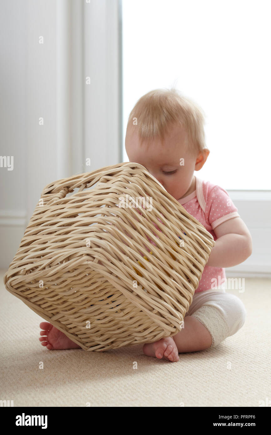 Baby (9 Monate) Suchen in wicker Aufbewahrungsbox Stockfoto