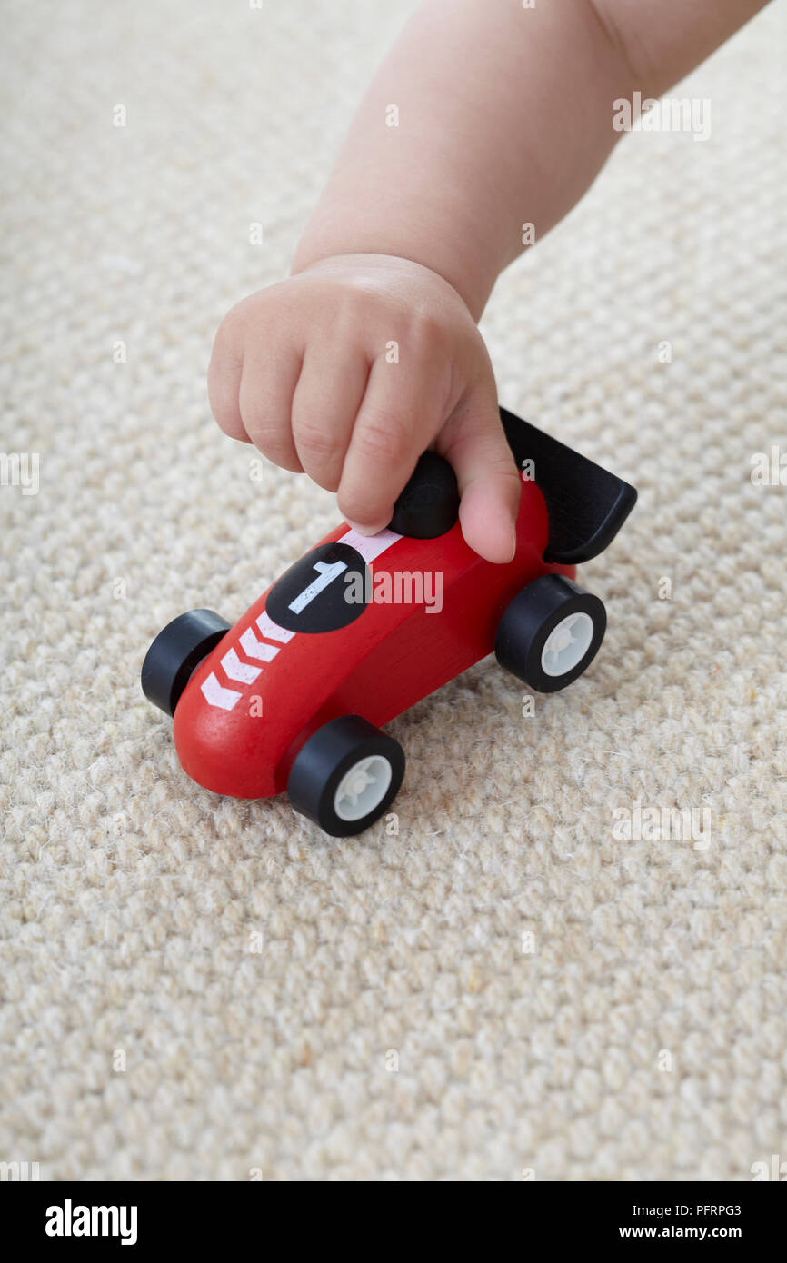 Die Hand des Babys, junge spielt mit Blue Spielzeugauto Stockfoto