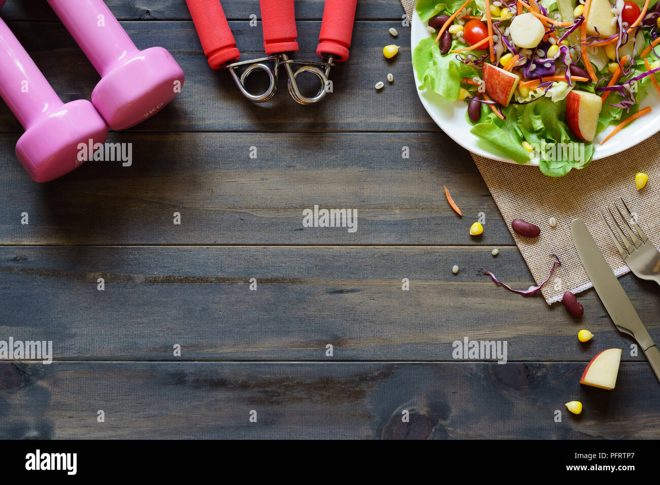 Frische, gesunde Salat mit Kurzhanteln und Übung Ausrüstung auf Holz Hintergrund top viwe mit kopieren. Für Diät, Fitness und Aktiv gesund lifest Stockfoto
