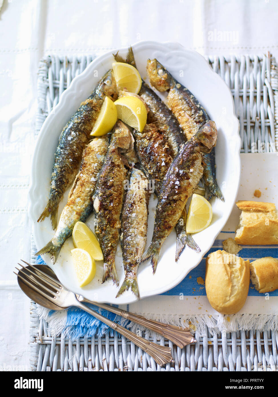 Sardinas a la plancha, gegrillte Sardinen mit Zitronen und Brot Stockfoto