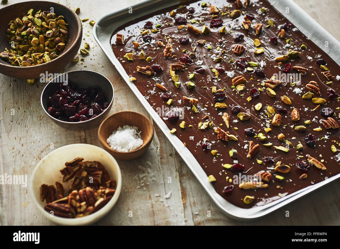 Dunkle Schokolade mit Rinde, Pekannüsse, Pistazien, Meersalz, Preiselbeeren Stockfoto