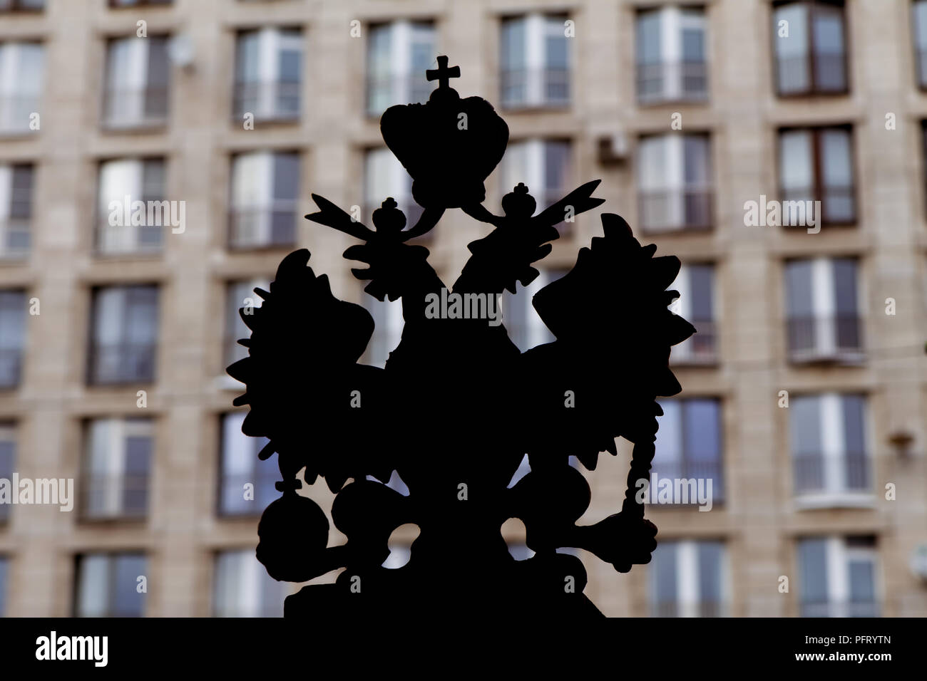 "Zwei Reiche": Silhouette des Wappens des Russischen Reiches mit einer Mauer von typischen High-sowjetischen Ära Gebäude im Hintergrund steigen; St. Petersbu Stockfoto