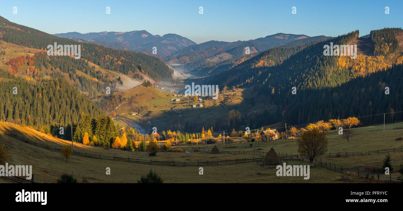 Farbenprächtige Herbstlandschaft im Bergdorf. Nebeliger morgen in den Karpaten, Ukraine Stockfoto
