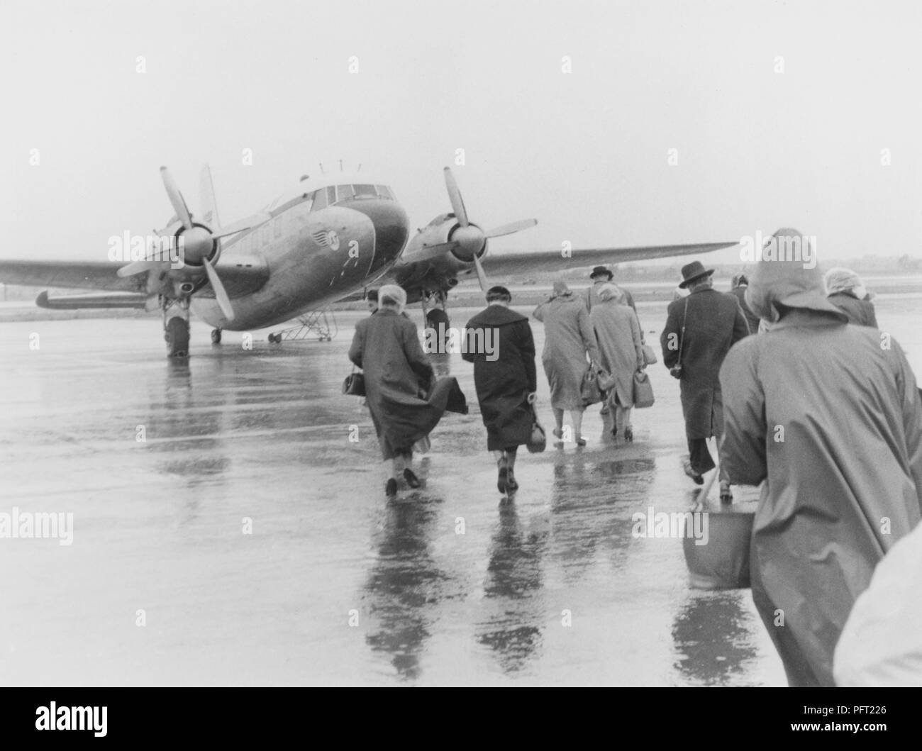 1950er Jahre Urlaub. Eine Gruppe von Menschen gehen in den strömenden Regen auf die wartende Flugzeug für Spanien gebunden. Schweden 1951. Ref 385 Stockfoto