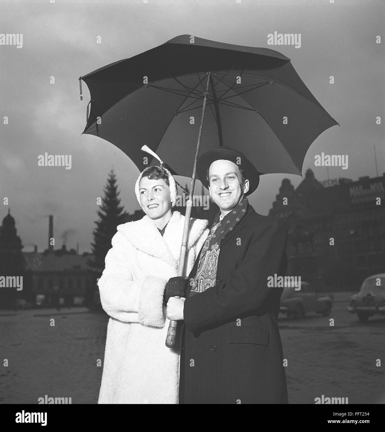 1950s Paar. Eine glücklich lächelnde Paar steht unter einem Sonnenschirm an einem regnerischen Tag. ref BB 11-5 Stockfoto