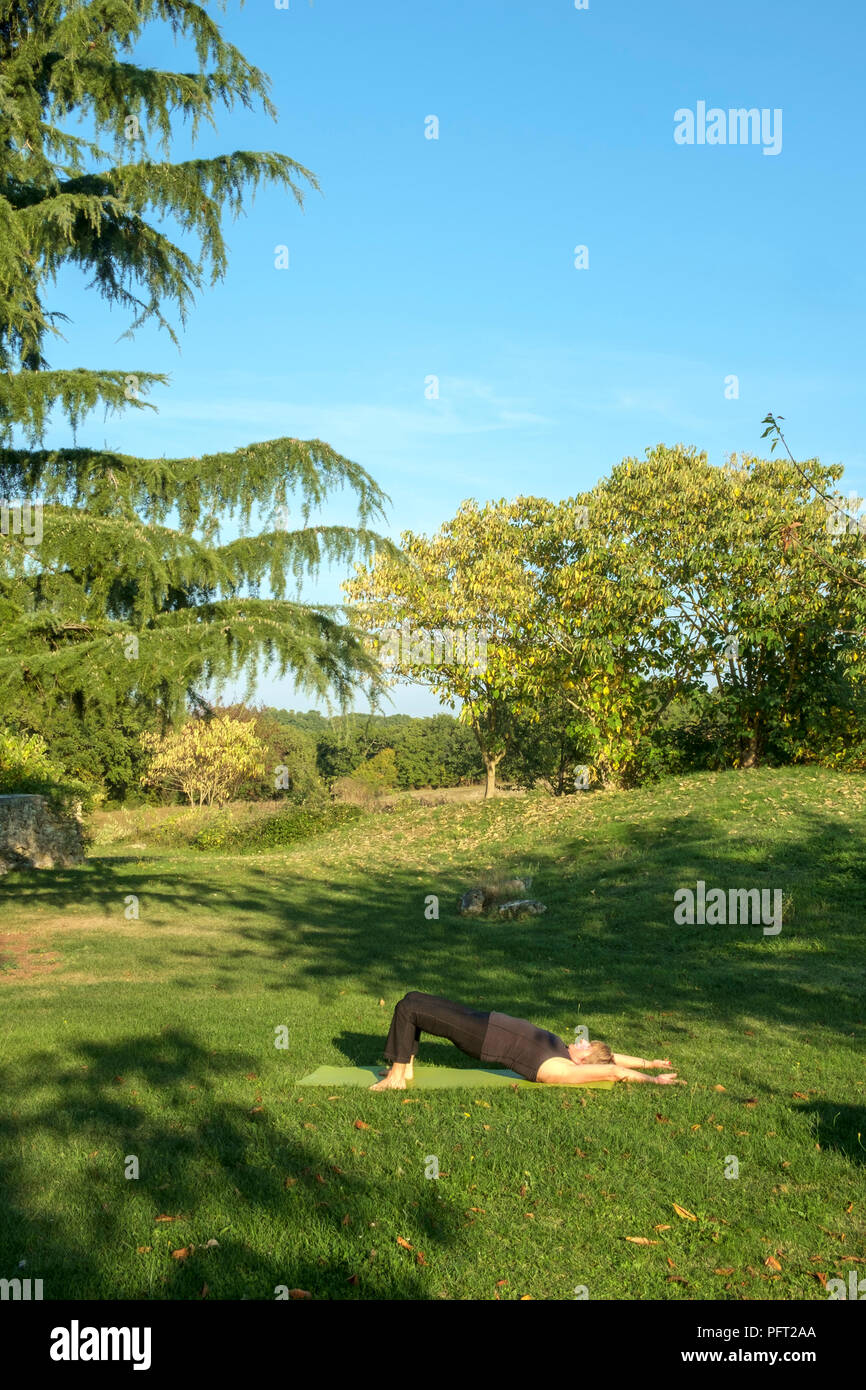 Von idyllischen ländlichen französischen Landschaft eine reife Frau übt ihre Yoga Positionen im schönen Herbst Sonne umgeben. Die Brücke dar. Stockfoto