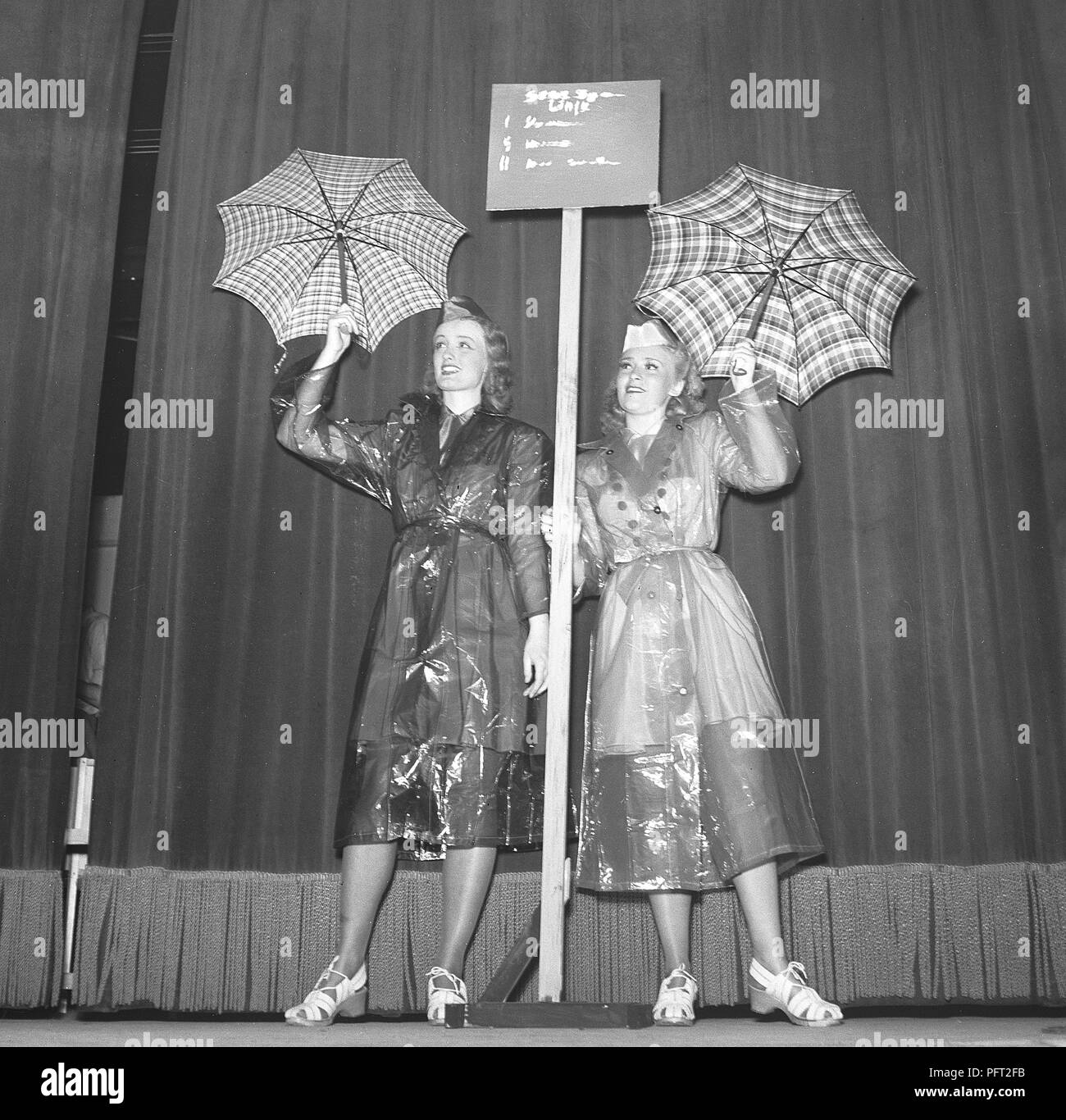 Frauen aus den 1940er Jahren in Regenmänteln. Zwei junge Frau in Regenmänteln aus Kunststoff zeigt ihnen Regenschirme. Schweden 1943 Ref. E47-5 Stockfoto