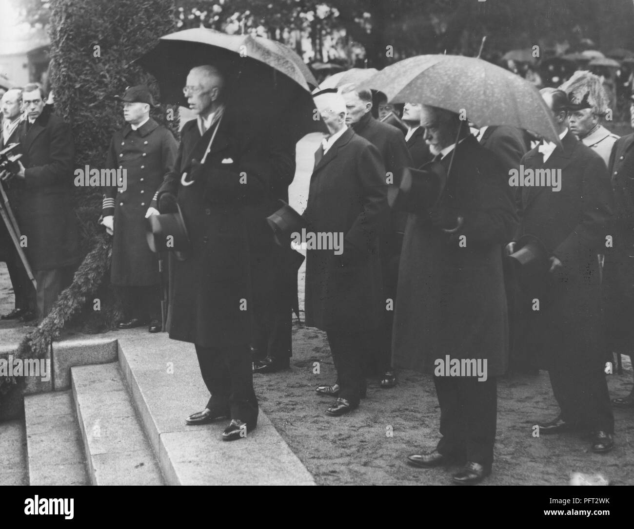 König Gustav V. von Schweden. Hier im Bild im Regen unter einem Sonnenschirm im Hafen von Stockholm warten auf das Schiff M/S Svensksund mit den Überresten von Andrée Ballon Expedition von 1897 zu kommen. Die Einrichtungen der Mitglieder wurden viele Jahre später 1930 auf der Insel Kvitøya auf Svalbard eingefroren gefunden. 1930 Stockfoto