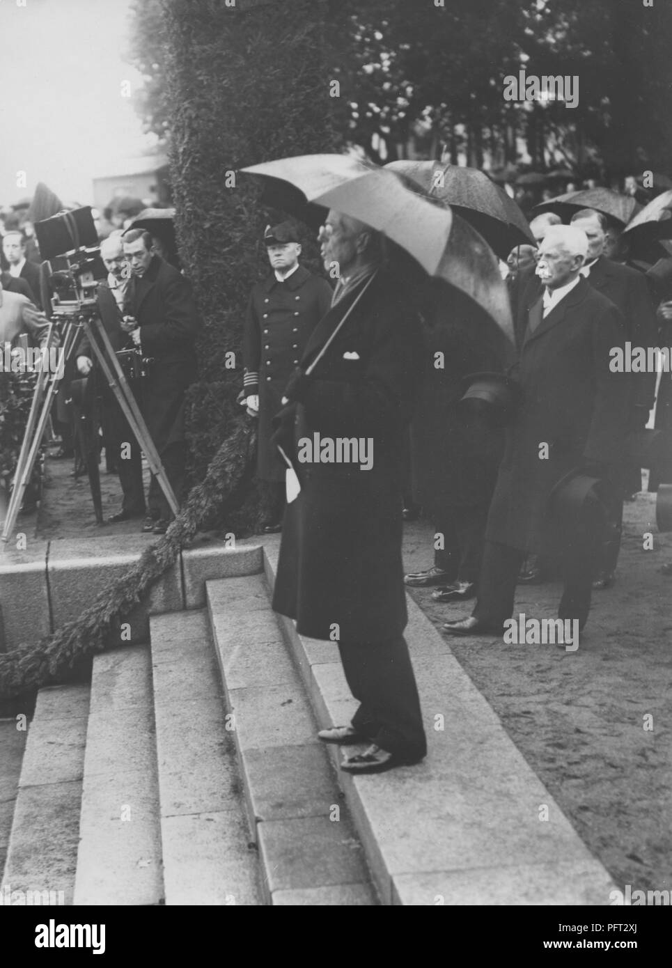 König Gustav V. von Schweden. Hier im Bild im Regen unter einem Sonnenschirm im Hafen von Stockholm darauf warten, für das Schiff M/S Svensksund mit den Überresten von Andrée Ballon Expedition von 1897 zu kommen. Die Einrichtungen der Mitglieder wurden viele Jahre später 1930 auf der Insel Kvitøya auf Svalbard eingefroren gefunden. 1930 Stockfoto