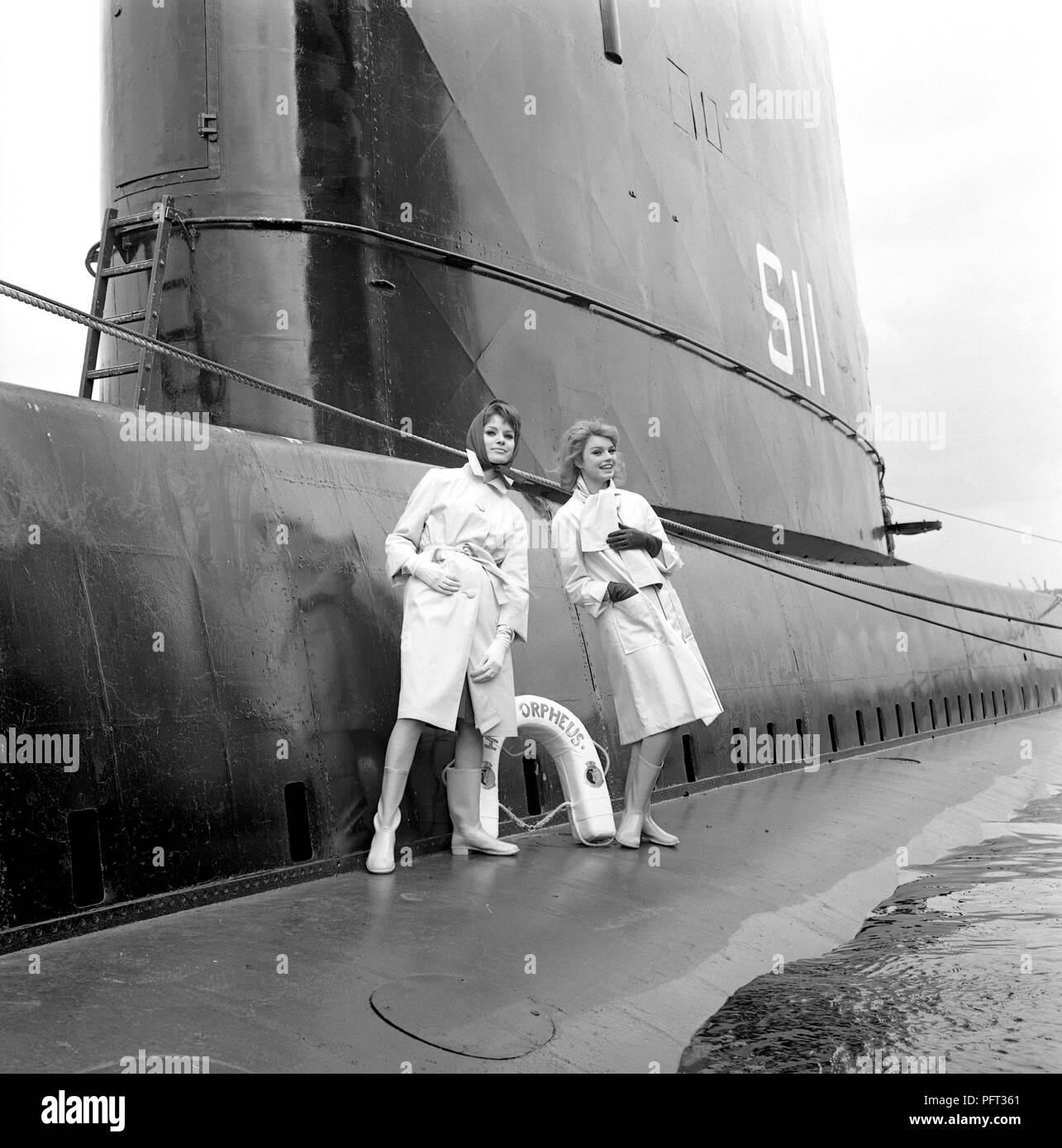 60er Jahre Mode. Zwei Models abgebildet an Bord des britischen U-Boot Orpheus. Das U-Boot liegt im Hafen von Stockholm verankert. Die Modelle tragen die herbste Mode Der regenjacken. Schweden Mai 1962 Stockfoto