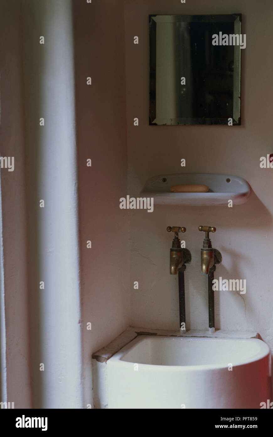 Kleine Ecke Waschbecken und Armaturen aus Messing mit einfachen über Spiegel Stockfoto