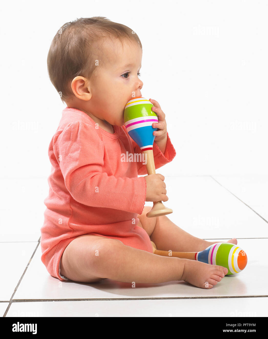 Baby Girl (8 Monate) mit Maraca in jeder hand Stockfoto