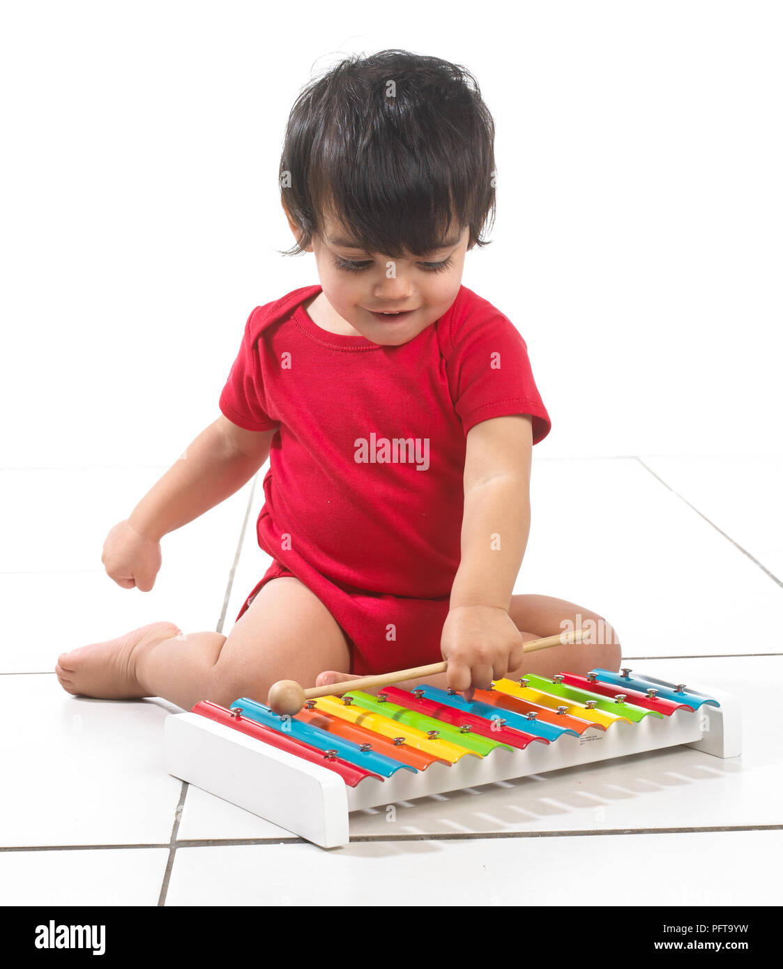 Junge (16 Monate) sitzt auf dem Boden spielen bunt Xylophon Stockfoto