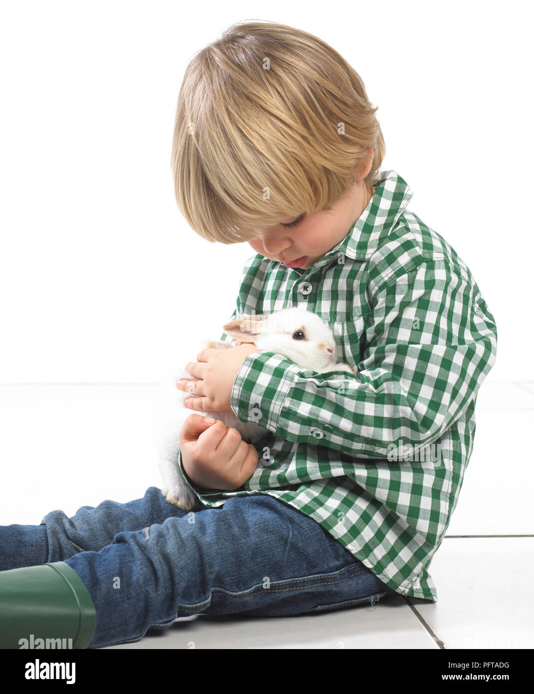 Kleiner Junge sitzt ein Kaninchen 2 Jahre halten Stockfoto