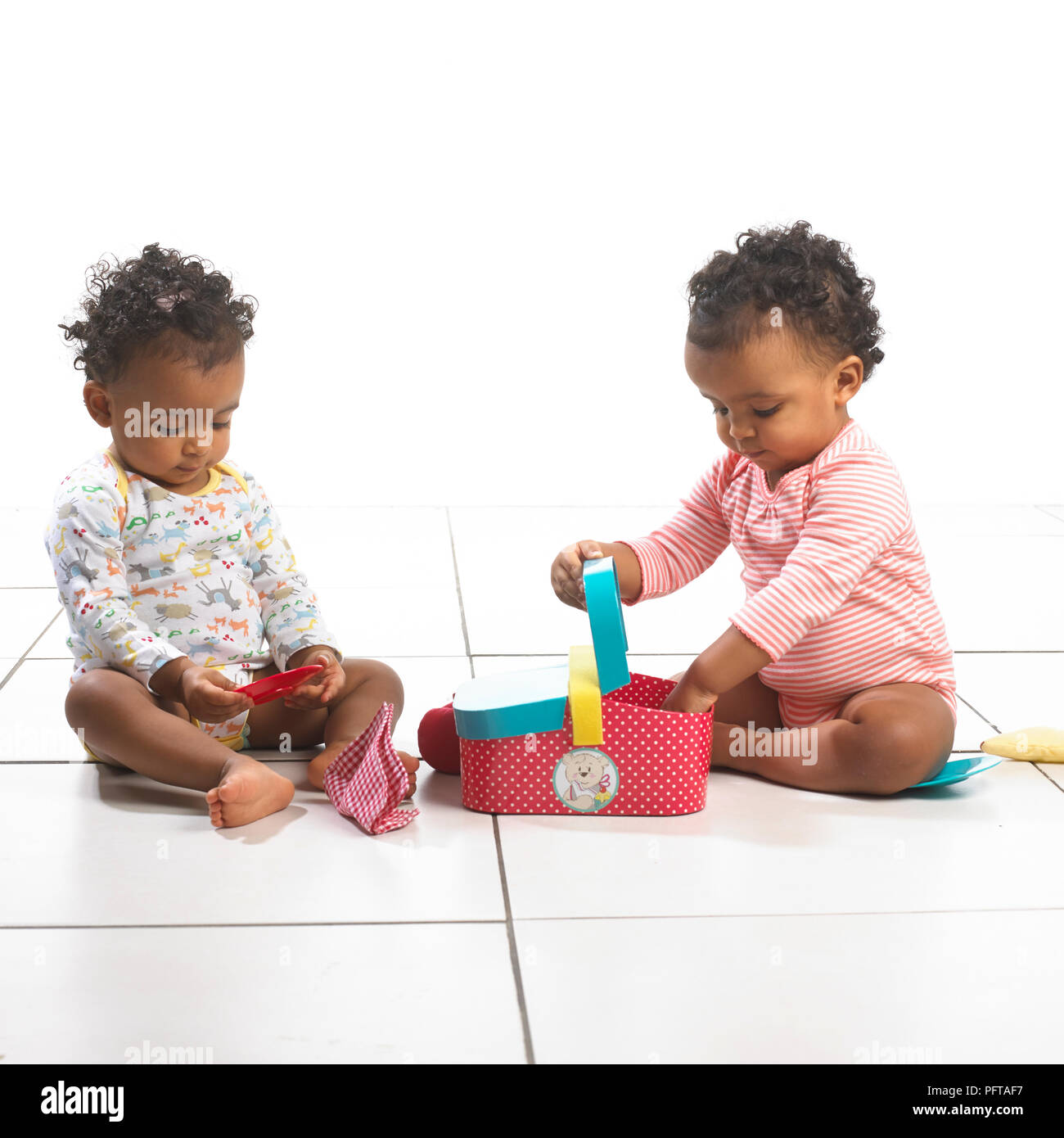 Zwei Mädchen und ein Junge sitzt Spielen mit Spielzeug Picknickkorb, 18 Monate Stockfoto