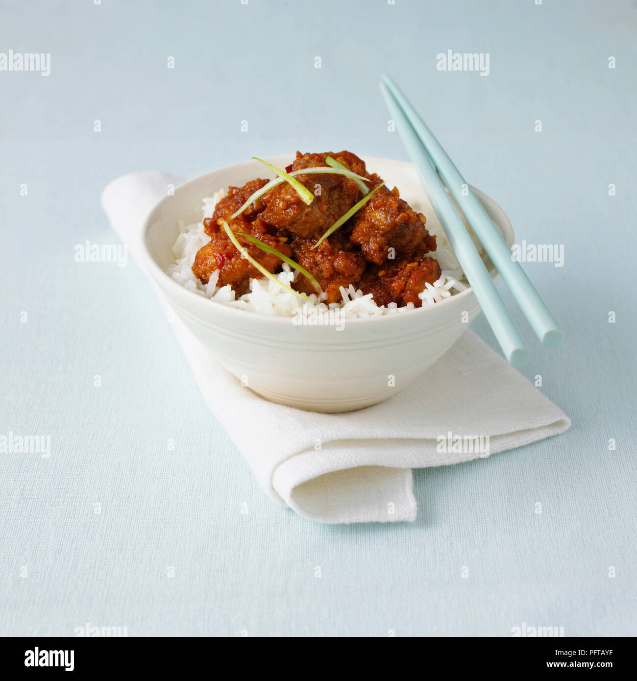 Huhn von General Tso serviert auf Bett aus Reis, Essstäbchen Stockfoto