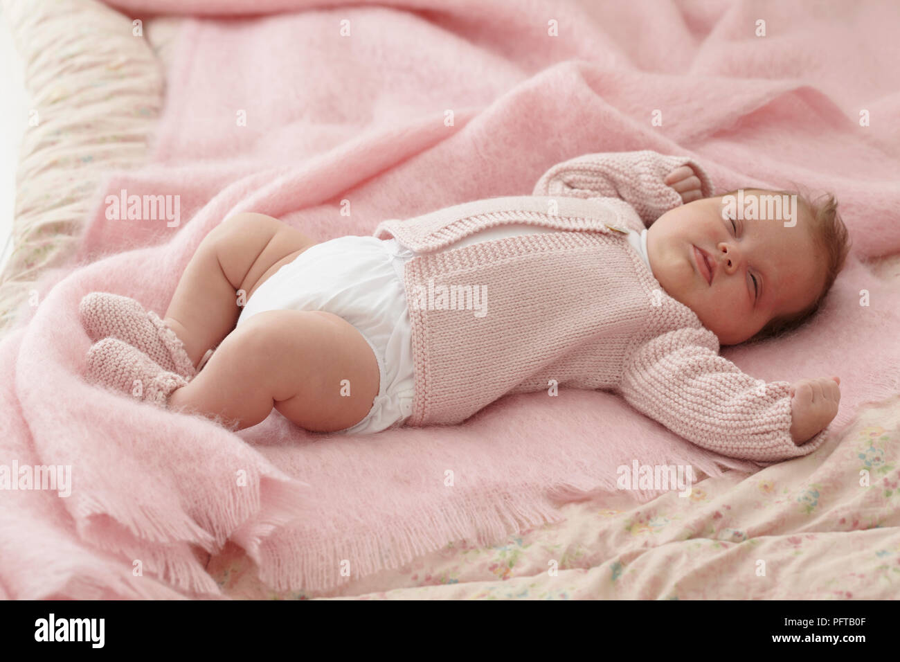 Baby Mädchen in rosa Strickjacke und Booties schlafend, 6 Wochen Stockfoto