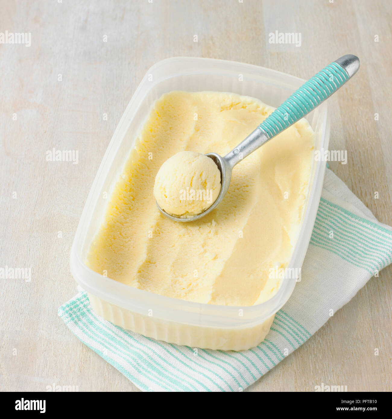 Wanne mit Vanilleeis und Schaufel Stockfoto