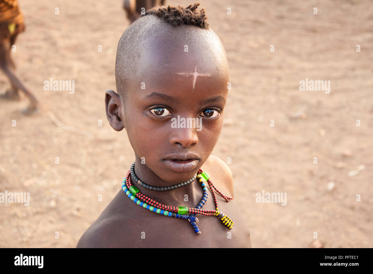 Schönen jungen afrikanischen Jungen mit traditionellen Halsketten mysteriöses Kreuz auf der Stirn von Hamar Stamm neugierig mit markanten glänzende Augen Stockfoto
