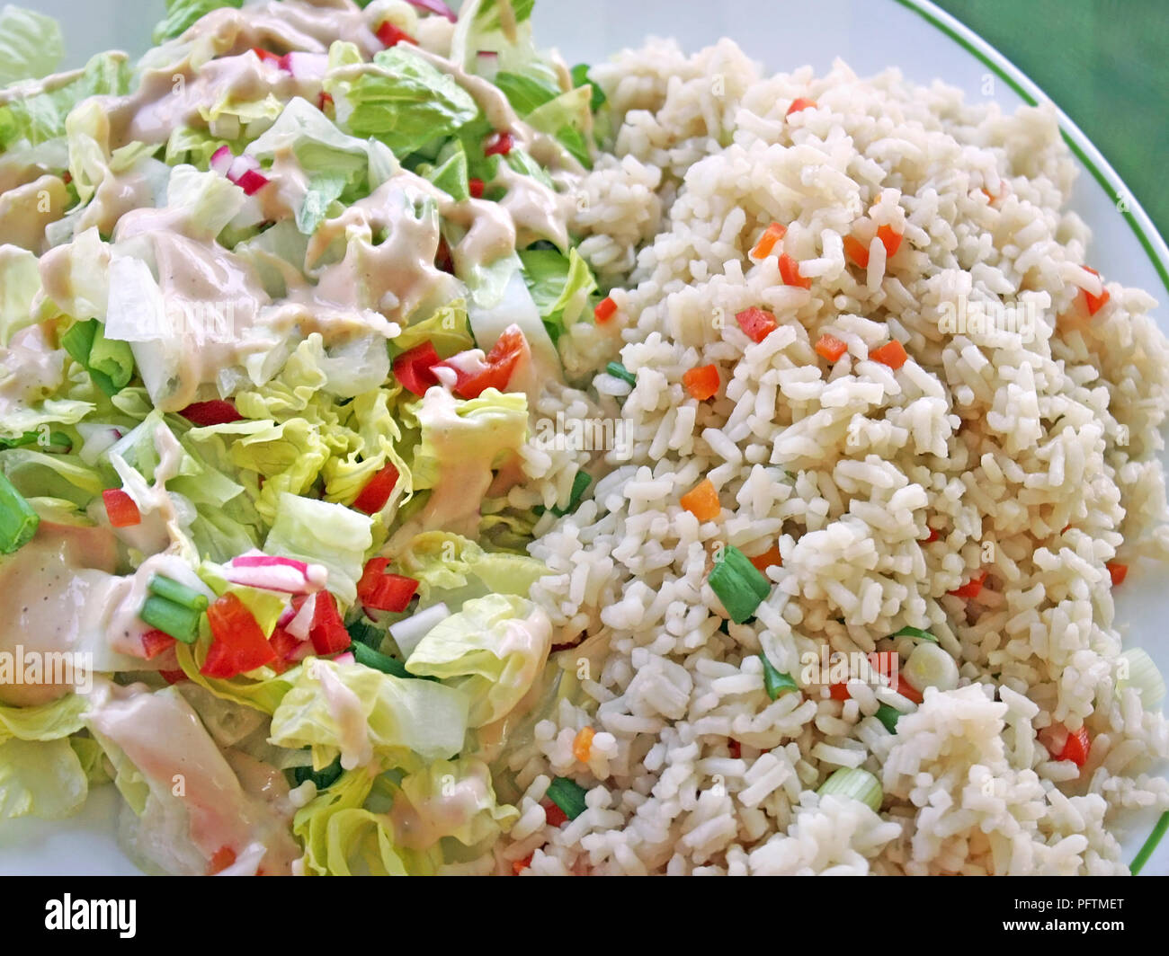 Gesunde Mahlzeit von Vollkorn brauner Reis mit Gemüse und einem frischen Gartensalat gekrönt mit einem cremige Dressing Stockfoto