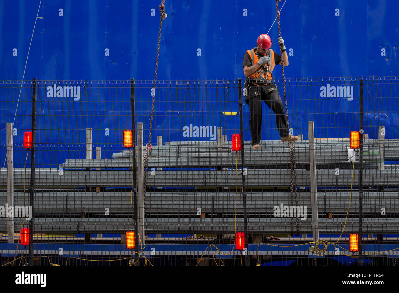 Ein Bauarbeiter überwacht das Anheben mit Hilfe eines Krans Fußboden neu in die oberen Stockwerken an der neuen Entwicklung hohe Bebauung bei 22 Bishopsgate in London City - der Capital District, am 21. August 2018 in London, England. 22 Bishopsgate ist ein kommerzielles Wolkenkratzer im Bau in London, Vereinigtes Königreich. Es wird ein prominenter Ort auf Bishopsgate besetzen, in der City von London Financial District, und ist 278 m hoch mit 62 Geschichten zu stehen. Das Projekt ersetzt eine frühere Plan für einen 288 m hohen Turm mit dem Namen Pinnacle, auf dem Bau im Jahr 2008 begonnen wurde, aber sus Stockfoto
